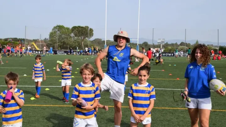 Niños y entrenadores participando en un festival de escuelas de rugby M12 en un campo al aire libre