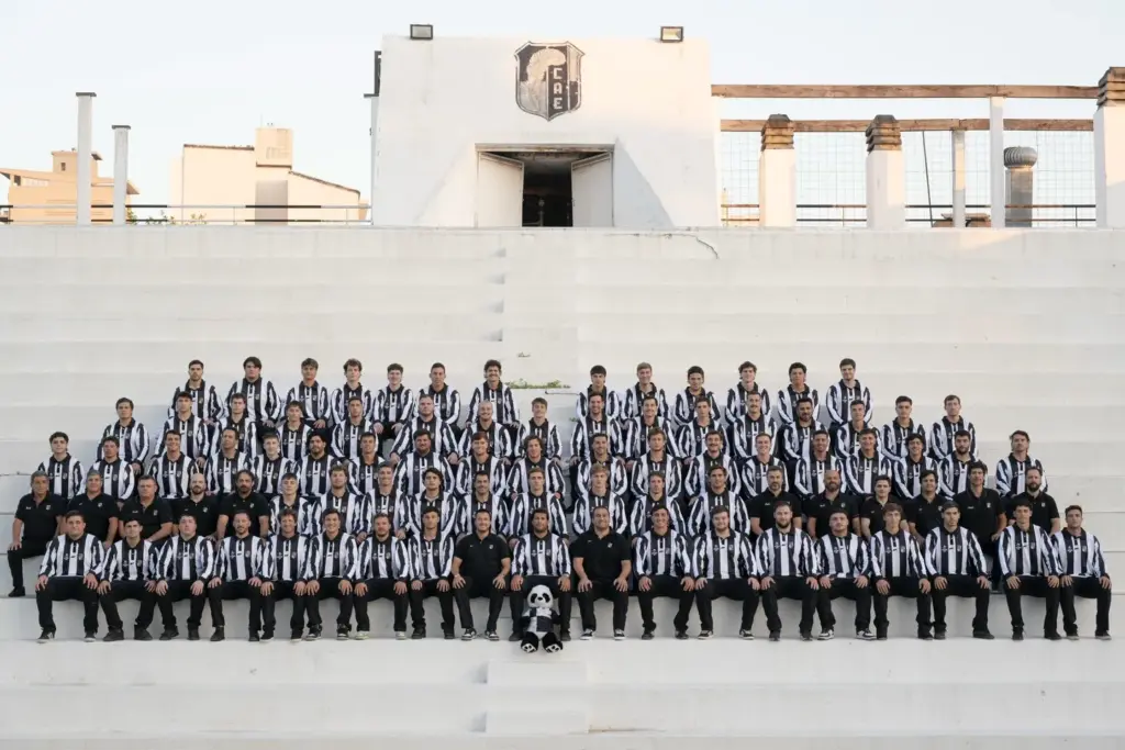 Plantel completo del Club Atlético Estudiantes de Paraná durante su gira internacional, posando en una tribuna con indumentaria oficial del club.