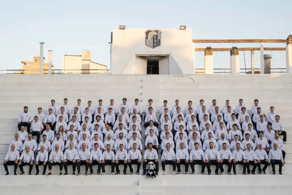 Plantel completo del Club Atlético Estudiantes de Paraná durante su gira internacional, posando en una tribuna con indumentaria oficial del club.