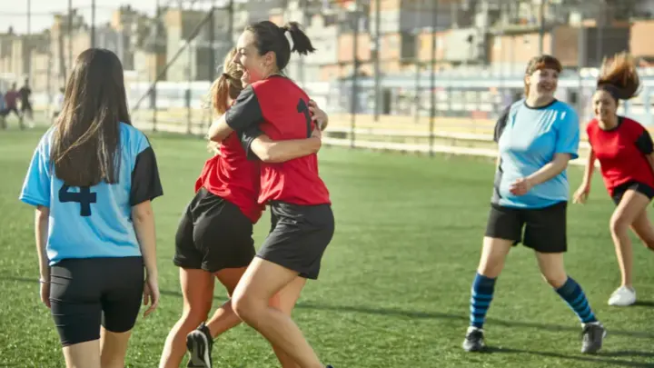 Partido de rugby femenino en acción durante un placaje, con jugadoras disputando el balón.